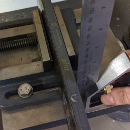 Mounting the rail in drill press vise, making sure it's perpendicular.